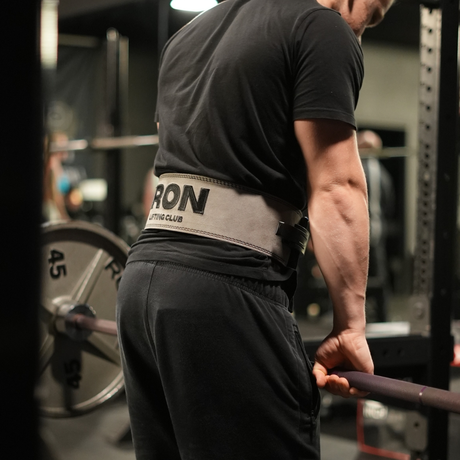 Person lifting weights with a weightlifting belt in a gym setting